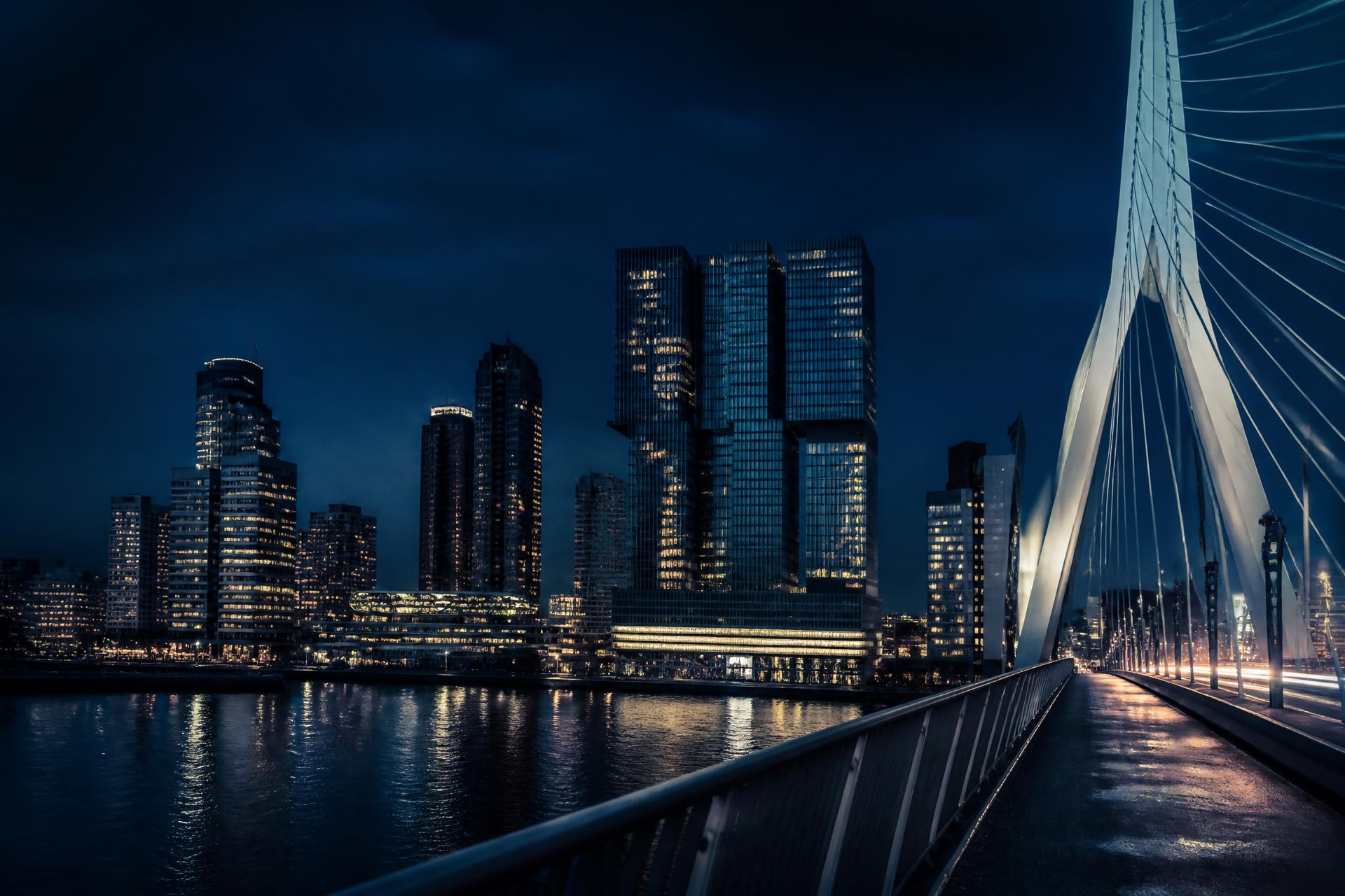 The Erasmus Bridge at night with the Rotterdam skyline behind it